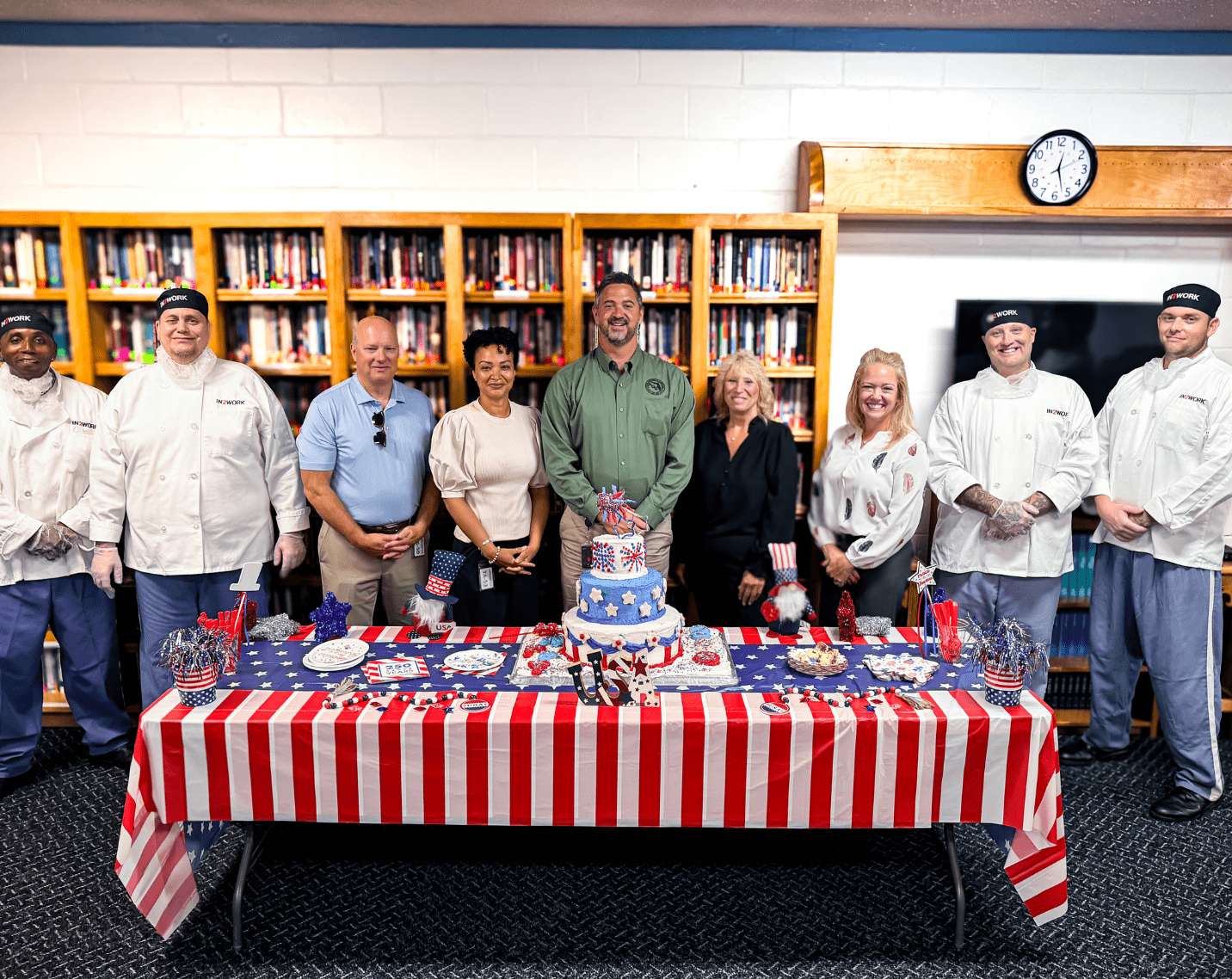 A group of people stand behind a table with a cake on it.